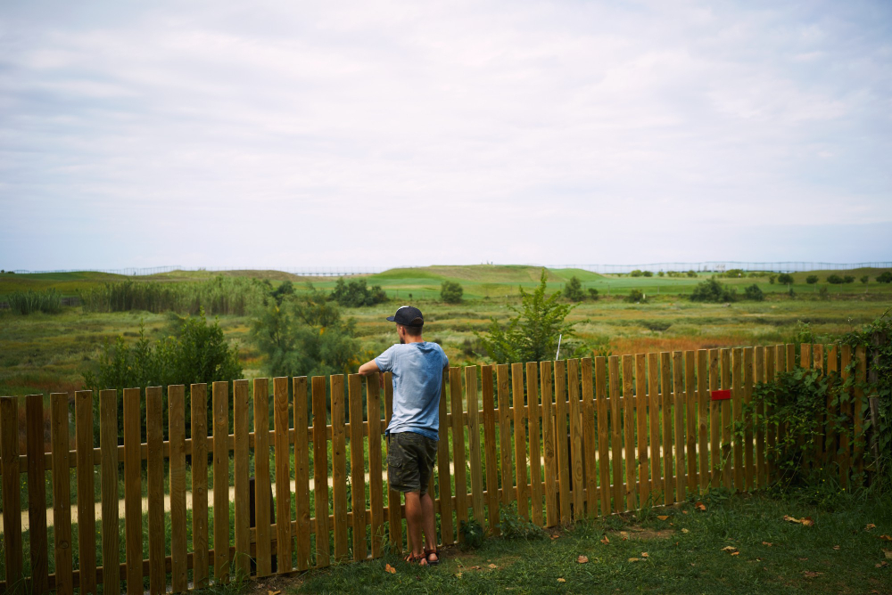 A man is standing behind the wooden fence