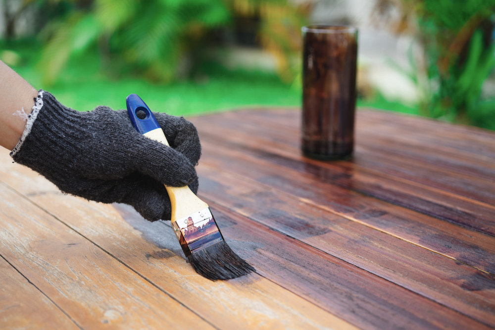 Man staining a wooden fence with a brush