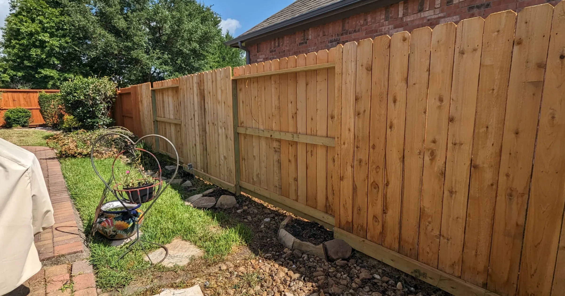 Blog 8 How to prepare for fence staining showing homeowner clearing items and furniture away from wooden fence in Houston backyard