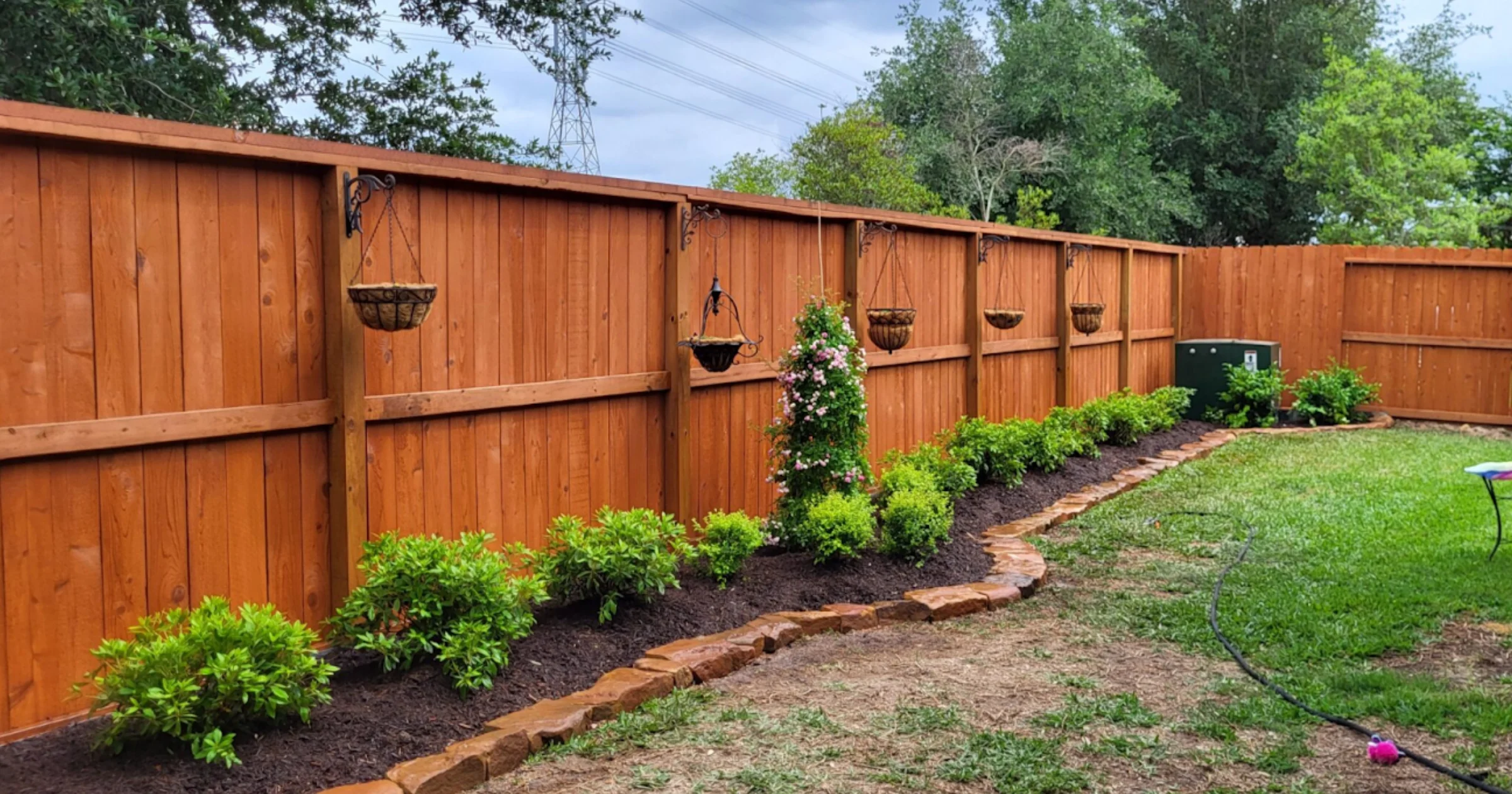 Blog 2 Beautifully stained cedar fence in rich brown color after professional fence staining service in Houston Texas backyard with decorative planters