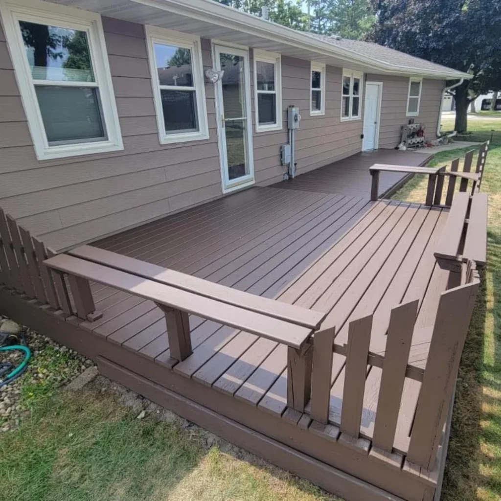 Professional deck staining Houston showing rich chocolate brown finish on wood deck surface railings residential property complete transformation gray house exterior