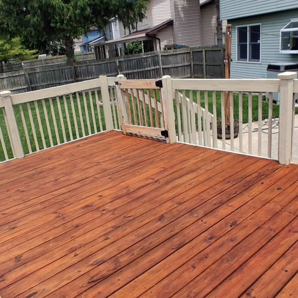 Professional deck staining Houston showing natural cedar tone finish wood deck surface with white painted railings residential backyard transformation complete