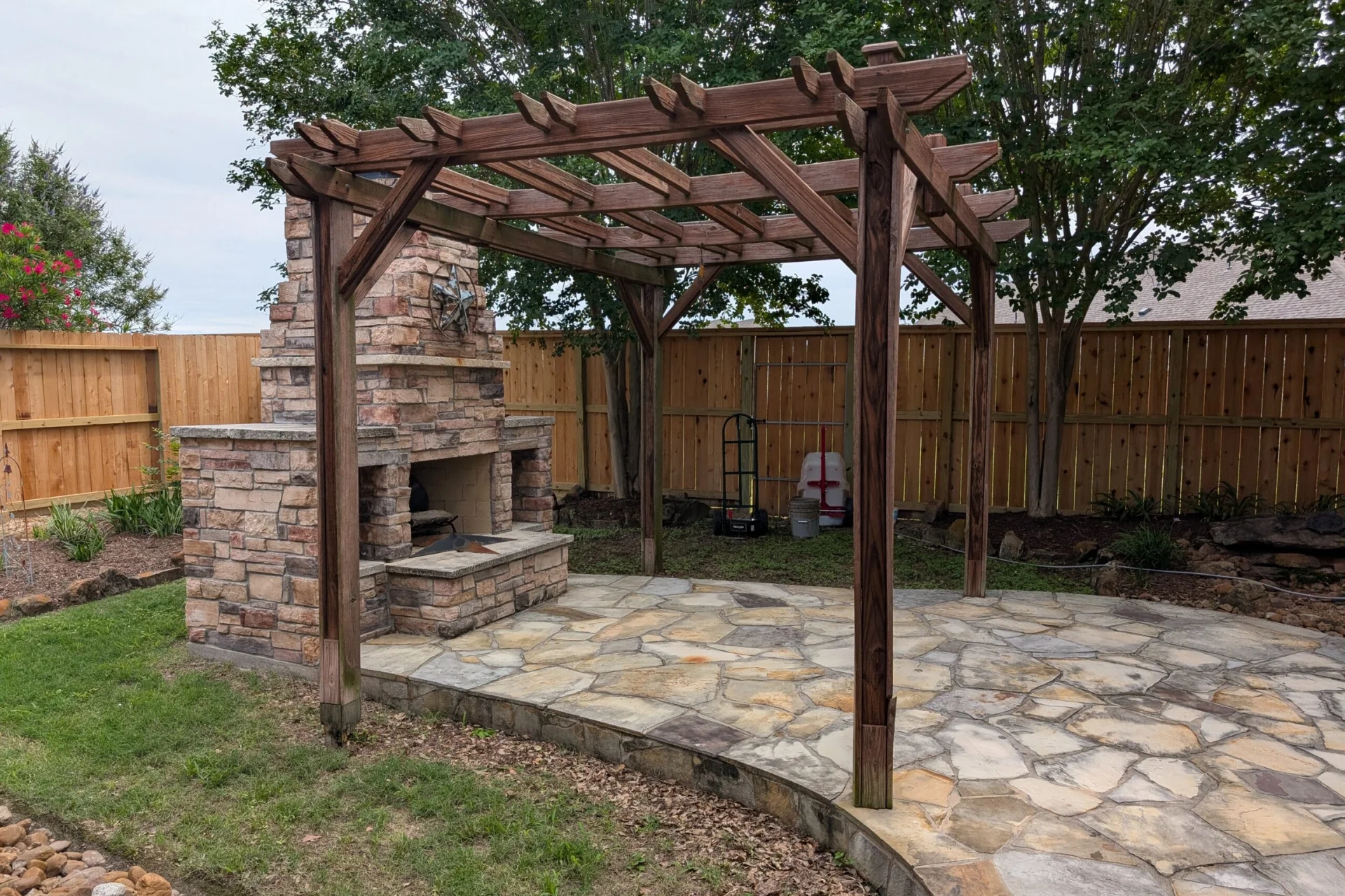 Professional pergola staining with rich mahogany brown stain protecting outdoor kitchen pergola and coordinated fence in Houston backyard