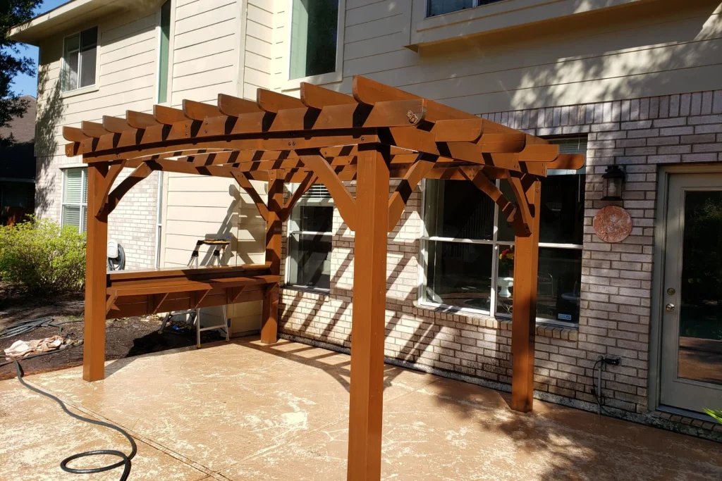 Pergola Staining 6 Professional pergola staining in progress showing fresh cedar stain application on overhead beams and posts during expert service