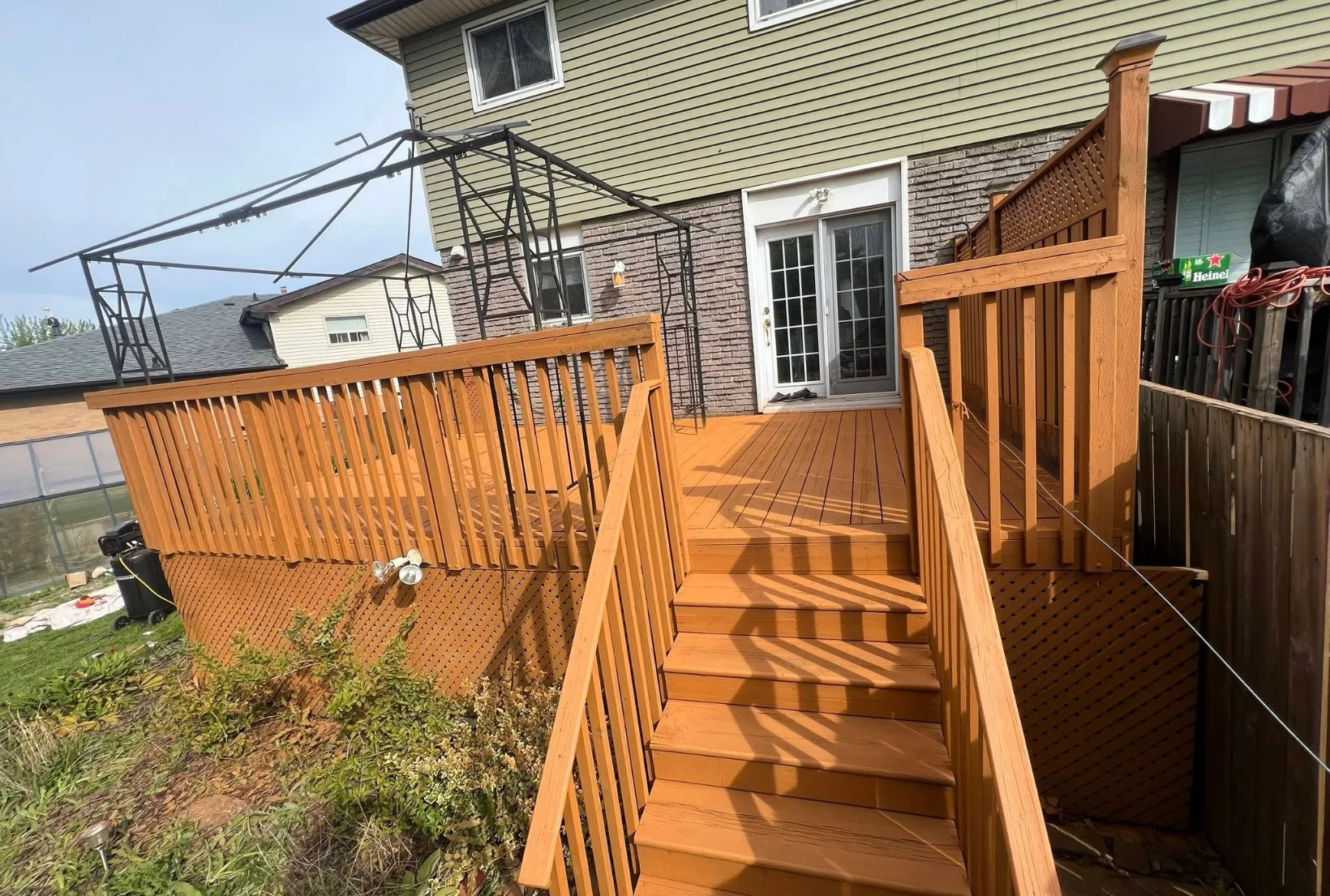 deck-stairs-staining-after-cedar-finish-houston Freshly stained deck with stairs railings and lattice in golden cedar finish after professional deck staining service