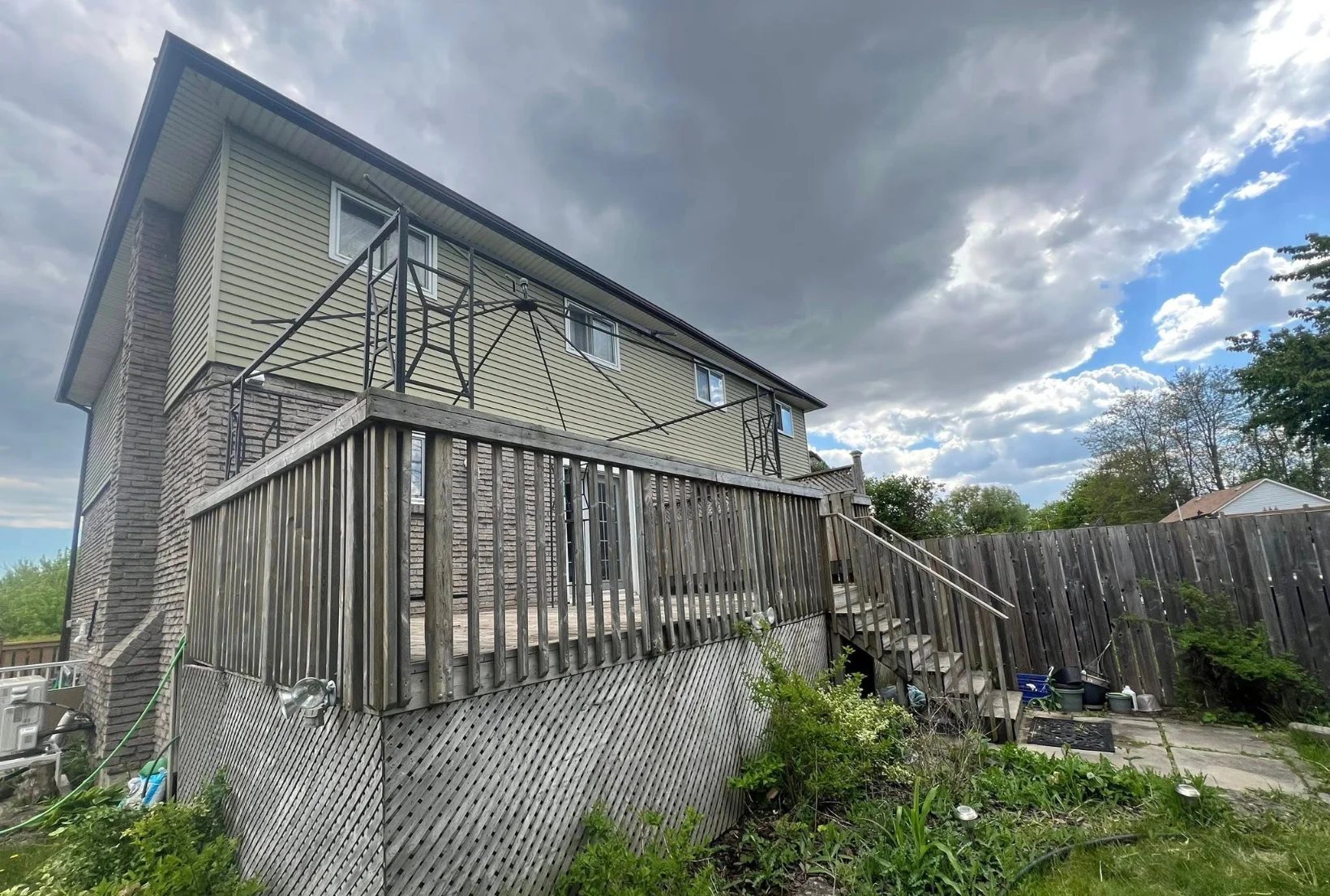 gray-elevated-deck-railings-before-staining-houston Gray weathered elevated deck with railings lattice skirting and fence before professional deck staining service