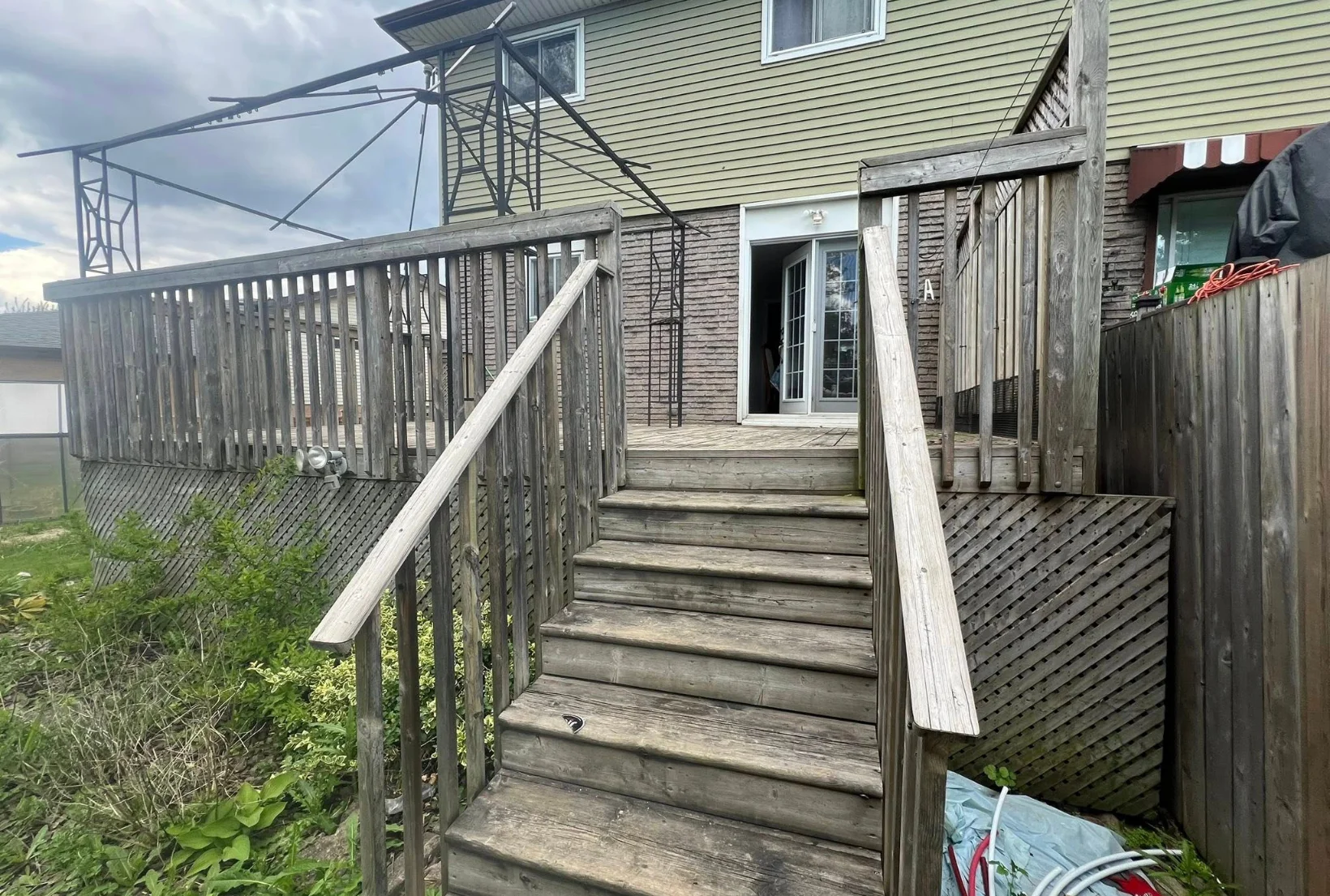 gray-weathered-deck-stairs-before-staining-houston Gray weathered wood deck with stairs railings and lattice skirting before professional deck staining restoration